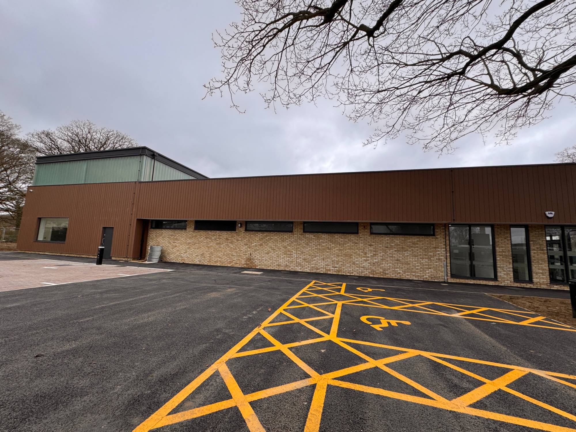 The Heathers community centre, a modern brick and brown-clad building, seen from the car park